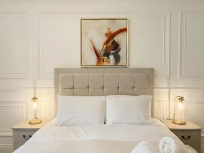 a bedroom with a white bed with a painting above it at Cozy 1 bed Blythswood Apartment in Glasgow
