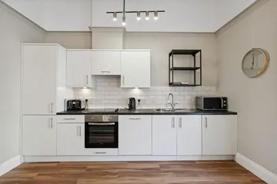 a white kitchen with white cabinets and a sink at (G5) Grand 1 bed Blythswood Apartment in Glasgow