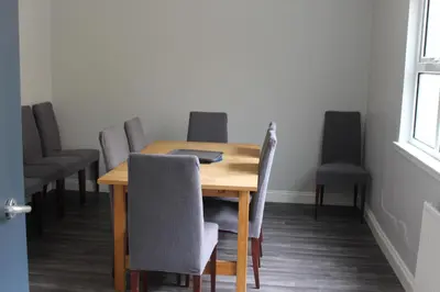 a dining room table with chairs and a laptop on it at Garnock 1 in Beith
