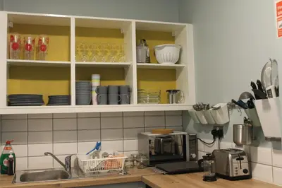 a kitchen with white cabinets with plates and glasses at Garnock 2 in Beith