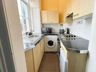a small kitchen with a washing machine and a washer at Cozy Studio Apartment of Glasgows West End in Glasgow