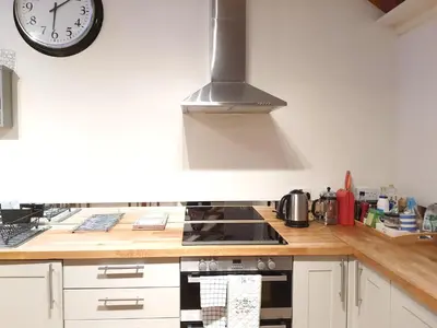 a kitchen with a stove and a clock on the wall at Edinburgh 2-Bedroom Cottage with Parking - Ground Floor in Edinburgh