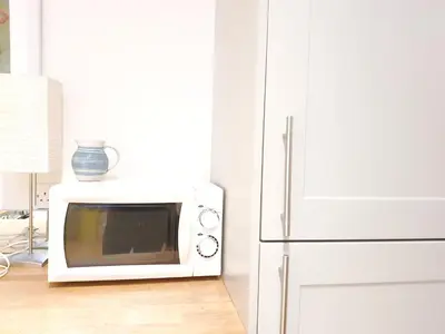 a microwave oven sitting on top of a refrigerator at Edinburgh 2-Bedroom Cottage with Parking - Ground Floor in Edinburgh