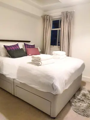 a bedroom with a large white bed with a window at Edinburgh 2-Bedroom Cottage with Parking - Ground Floor in Edinburgh