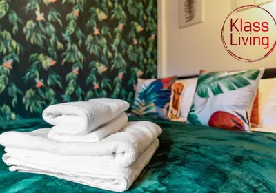 a pile of towels sitting on top of a bed at Uddingston Apartment by Klass Living in Uddingston