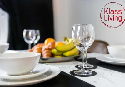 a table with a plate of fruit and two wine glasses at Uddingston Apartment by Klass Living in Uddingston