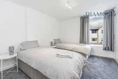 a white bedroom with a bed and a window at FOUNDRY - 2 Bedrooms, Fully Equipped, Free Parking, WiFi, FAVOURITE for Contractors, Long Stays Welcome, Food, Bars, Shops by Diamond Short Lets in Dunfermline