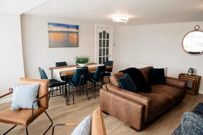 a living room with a couch and a table and chairs at Otterburn House in Rothesay