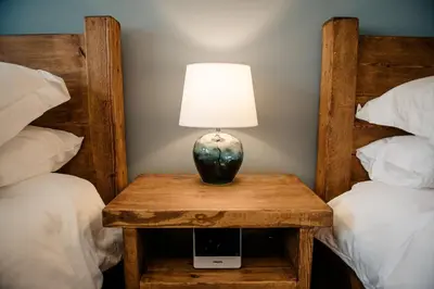 a table with a lamp on it next to two beds at Otterburn House in Rothesay
