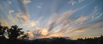 a cloudy sky at sunset with a tree and mountains at Aquila Retreats in Comrie