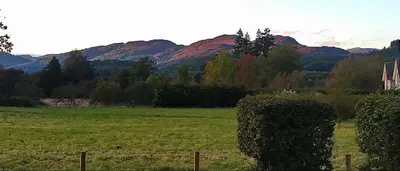 a field with trees and mountains in the background at Aquila Retreats in Comrie