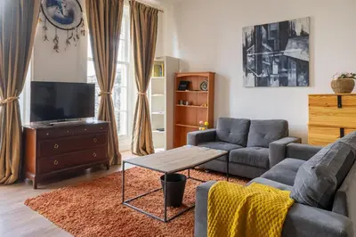 a living room with a couch and a tv at Bright High-Ceiling 2BD Flat - Central Edinburgh! in Edinburgh