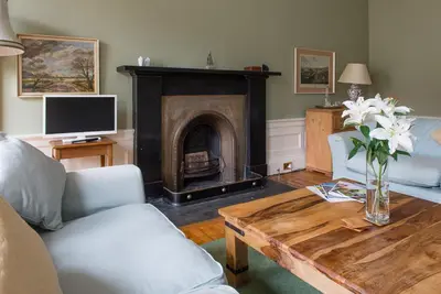 a living room with a fireplace and a table with flowers at Unique Edinburgh New Town Apartment near Princes Street in Edinburgh