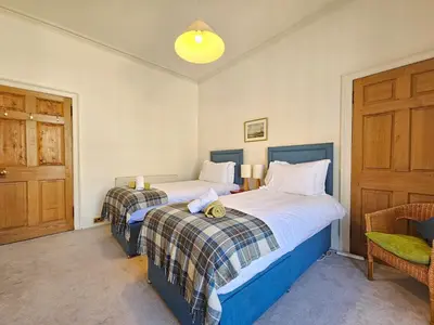 two twin beds in a room with a door at Unique Edinburgh New Town Apartment near Princes Street in Edinburgh