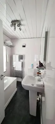 a white bathroom with a tub and a sink and a mirror at Cadillac Kustomz Guest House in Rothesay