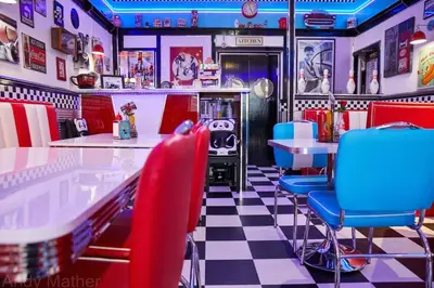 a diner with red and blue chairs and a checkered floor at Cadillac Kustomz Guest House in Rothesay