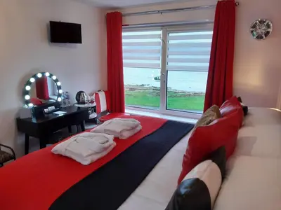 a bedroom with a bed and a window with the ocean at Cadillac Kustomz Guest House in Rothesay