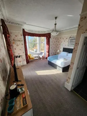 a bedroom with a bed and a desk with a television at King's Knoll Hotel in Oban