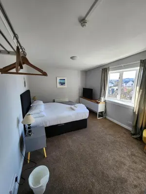 a bedroom with a large bed and two windows at King's Knoll Hotel in Oban