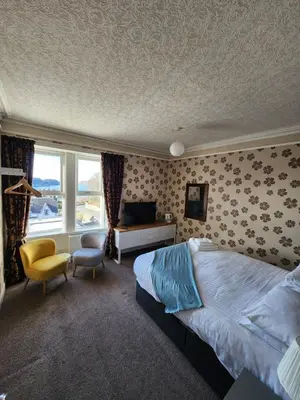 a bedroom with a bed and a desk and a window at King's Knoll Hotel in Oban