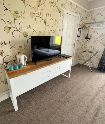 a living room with a flat screen tv on a dresser at King's Knoll Hotel in Oban