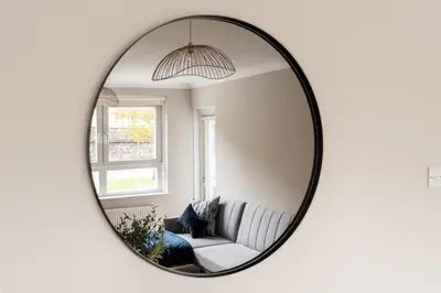 a mirror reflecting a living room with a couch at Shaw Apartment in Glasgow