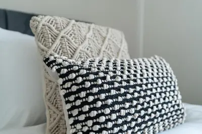 a black and white crochet pillow sitting on a bed at Shaw Apartment in Glasgow