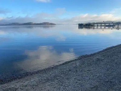 a large body of water with a pier in the distance at Mackie lodge in Luss