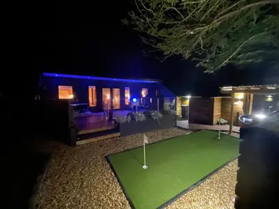 a house with a putting green at night at Mackie lodge in Luss