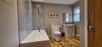 a bathroom with a tub and a toilet and a sink at Ben Vorlich Cottage in Tarbet