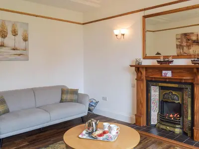 a living room with a couch and a fireplace at Wayside Cottage in Dunoon