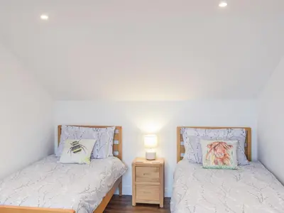 two twin beds in a bedroom with a night stand at Wayside Cottage in Dunoon