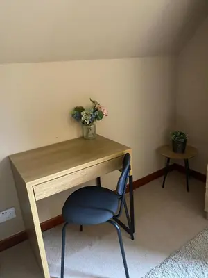 a desk with a blue chair and a vase of flowers at Wilmar Lodge in Arrochar
