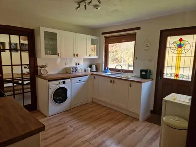 a kitchen with a washing machine and a washer at Wilmar Lodge in Arrochar
