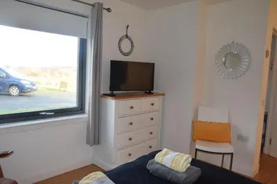 a bedroom with a tv and a dresser with a window at The Stable at Drumachro in Isle of Gigha