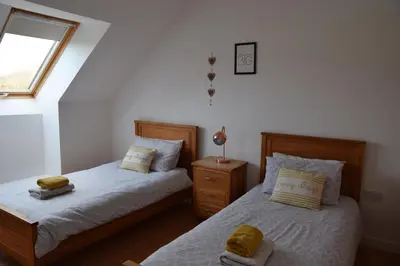 a bedroom with two twin beds and a window at The Barn at Drumachro in Isle of Gigha