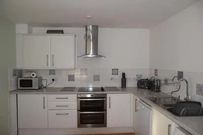 a kitchen with white cabinets and a stove top oven at The Barn at Drumachro in Isle of Gigha