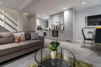 a living room with a couch and a glass table at Bell Apartment in Airdrie