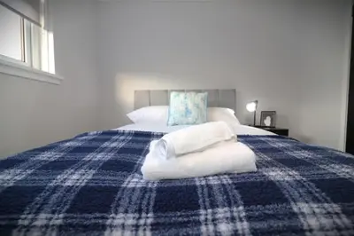 a blue and white bed with towels on it at Signature - Glen Garry House in East Kilbride