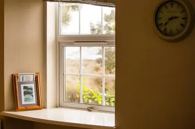 a clock on a wall next to a window at Beautiful spacious old schoolhouse with stunning sea views and beach nearby in Port Bannatyne