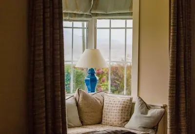 a window with a blue lamp in a living room at Beautiful spacious old schoolhouse with stunning sea views and beach nearby in Port Bannatyne
