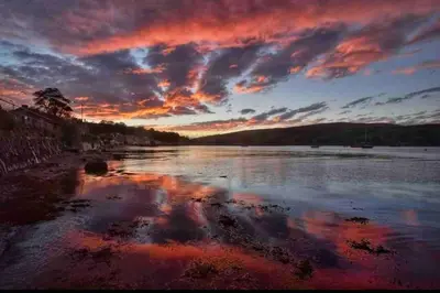 a sunset over a body of water with a cloudy sky at Beautiful spacious old schoolhouse with stunning sea views and beach nearby in Port Bannatyne