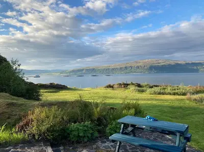 a blue bench sitting next to a body of water at Alltcreich in Craignure