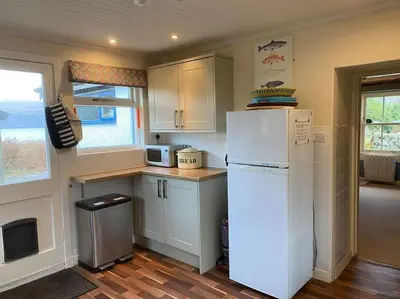 a kitchen with a white refrigerator and a window at Alltcreich in Craignure
