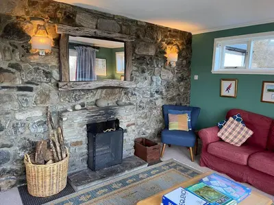 a living room with a stone fireplace and a red couch at Alltcreich in Craignure