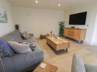 a living room with a couch and a flat screen tv at Thorneydyke Cottage in Stirling