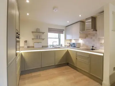 a kitchen with white cabinets and a sink at Thorneydyke Cottage in Stirling