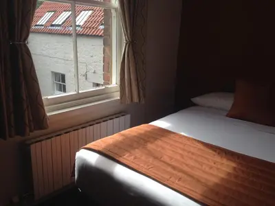 a bedroom with a bed next to a window at Aberdour Hotel, Stables Rooms & Beer Garden in Aberdour