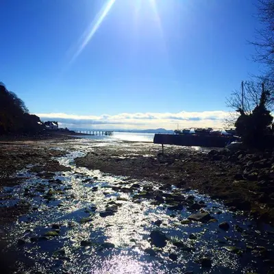 a beach with snow on the ground and the sun at Aberdour Hotel, Stables Rooms & Beer Garden in Aberdour