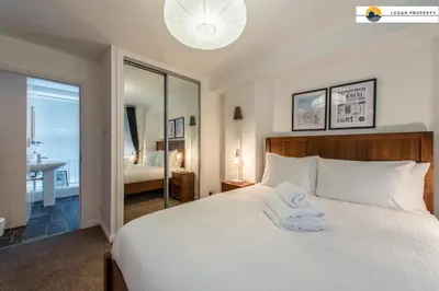 a bedroom with a large white bed with a mirror at Lady Wynd - 1 bed apartment in Edinburgh